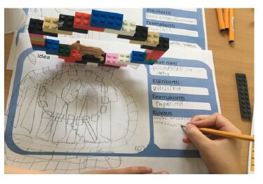 A child's LEGO and sketch prototype of a zoo enrichment technology on an enclosure plan